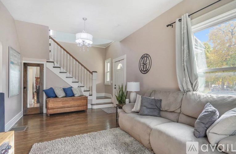 A living room with a couch, a staircase, and a window.