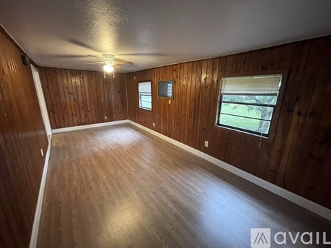 A room with wooden walls and floor and a window with blinds.