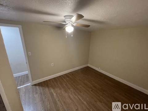 A room with a ceiling fan and wooden flooring.