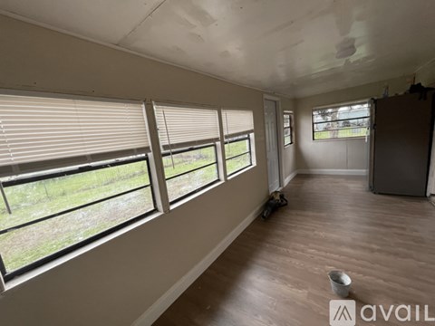 A room with wooden floors and large windows overlooking a grassy area.