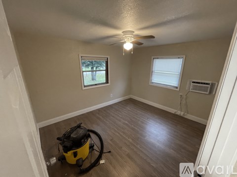 A room with a ceiling fan and two windows.
