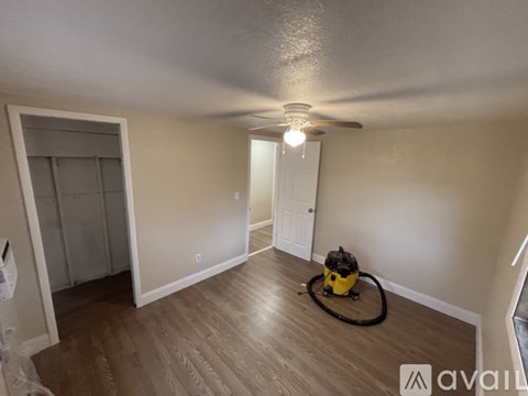 A room with a fan and a vacuum cleaner on the floor.