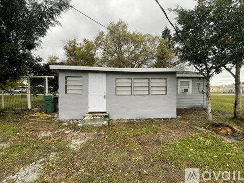 A small white house with a green container in front of it.