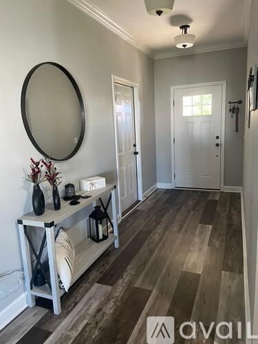 A hallway with a white door and a round mirror on the wall.