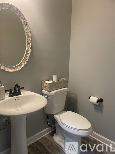 A bathroom with a toilet, sink, and mirror.