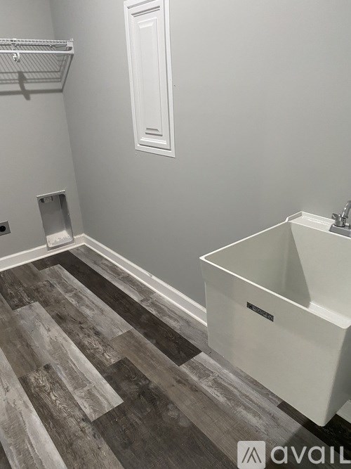 A bathroom with a white tub and grey wood flooring.