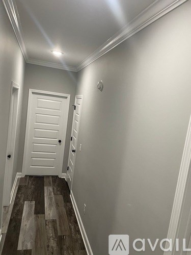 A hallway with a white door and wooden floors.