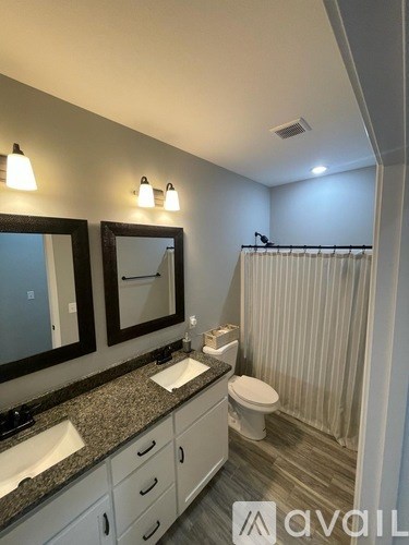 A bathroom with a sink, mirror, toilet and shower.
