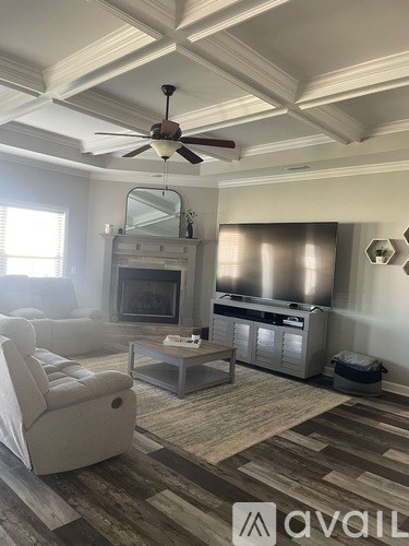 A living room with a fireplace and a ceiling fan.