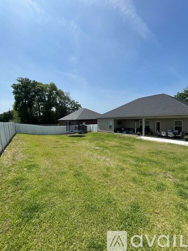 A large grassy yard with a house and a fence in the background.