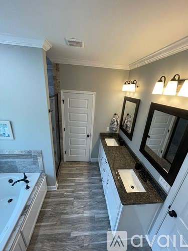A bathroom with a tub, sink, and mirror.