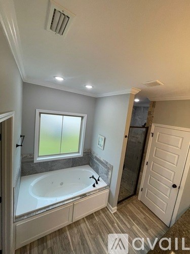 A bathroom with a large tub and a window overlooking a green field.