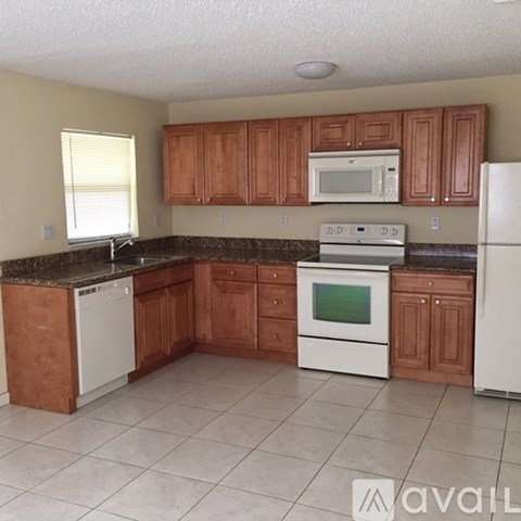 A kitchen with brown cabinets and white appliances.