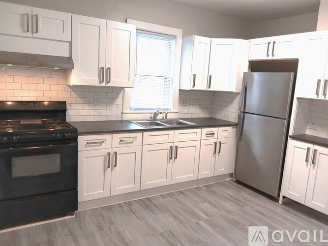 A kitchen with white cabinets and a black stove top oven.