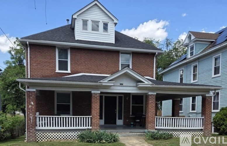 A two-story house with a red brick exterior and a white porch.