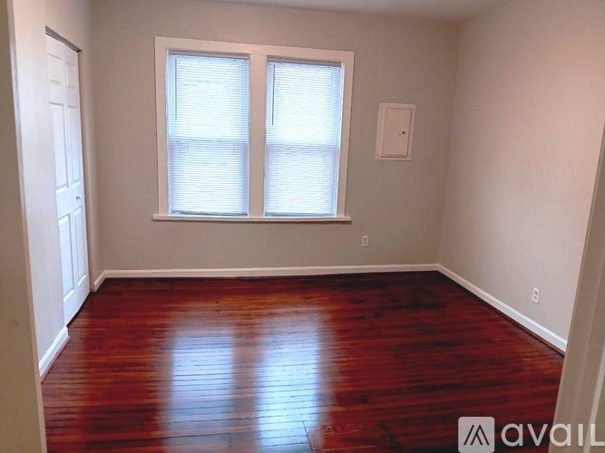 A room with wooden floors and two windows.
