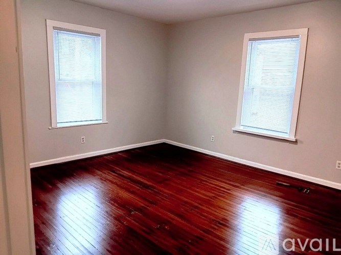 A room with wooden floors and two windows.