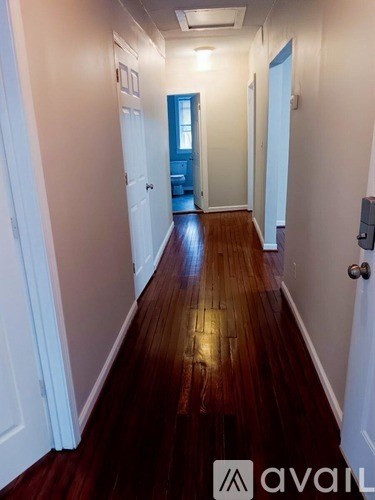 A hallway with wood floors and white walls.