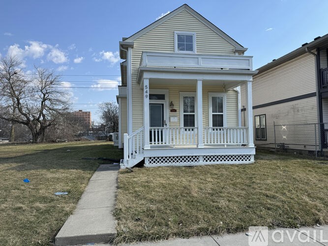 A small white house with a porch and a walkway leading to the front door.