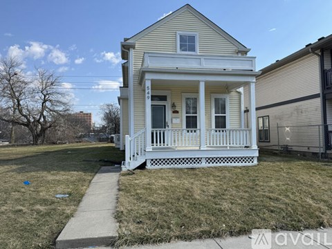A small white house with a porch and a walkway leading to the front door.