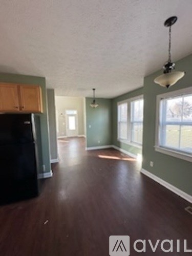 A kitchen with a black fridge and wooden cabinets.