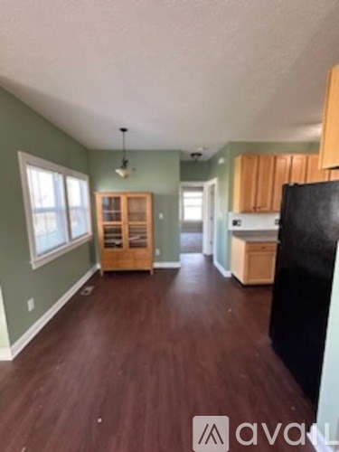 A kitchen with a black refrigerator and wooden cabinets.