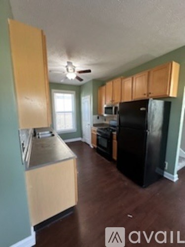 A kitchen with a black refrigerator and wooden cabinets.