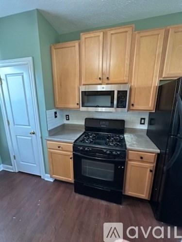 A kitchen with wooden cabinets and black appliances.