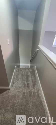 A hallway with a carpeted floor and a window on the right side.