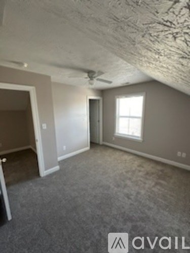 A room with a window and a carpeted floor.