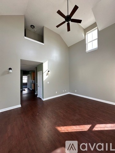 A room with a ceiling fan and a window letting in sunlight.