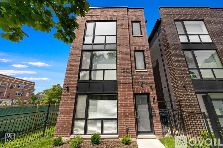 A tall brick building with a black fence in front.