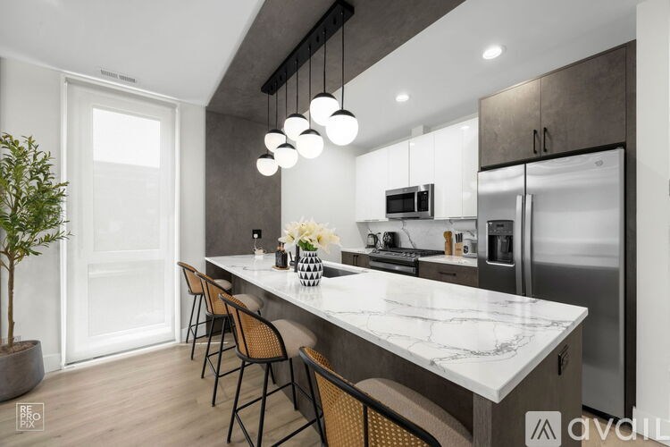 A modern kitchen with a marble countertop and stainless steel appliances.