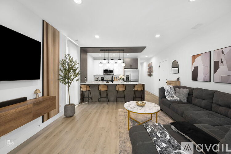 A modern living room with a black sofa and a wooden floor.