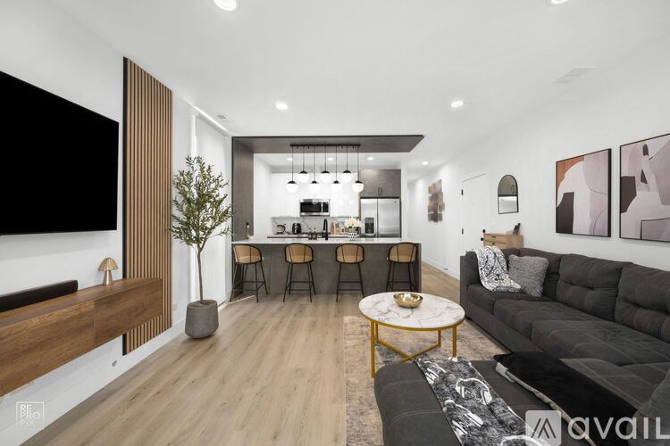 A modern living room with a black sofa and a wooden floor.