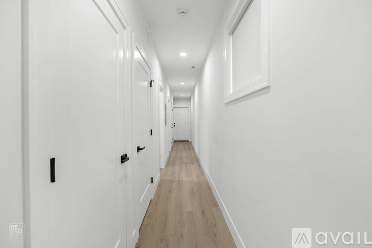 A long hallway with white walls and wood flooring.