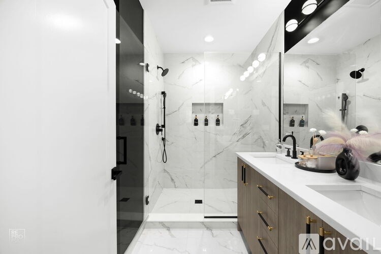 A bathroom with a marble floor and walls, a walk-in shower, and a vanity with a sink and mirror.