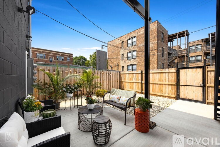 A patio with a black sofa, a small table, and a potted plant.
