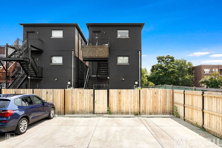 A blue car is parked in a driveway in front of a two-story house.