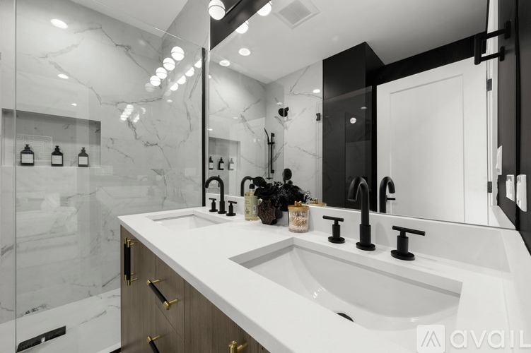 A modern bathroom with a marble countertop and a large mirror.