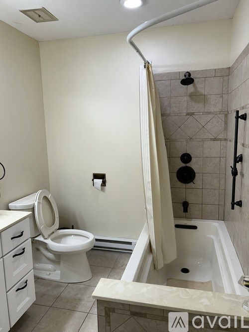 A bathroom with a toilet, tub, and a towel rack.