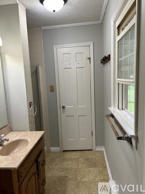 A bathroom with a sink, mirror, and a door.