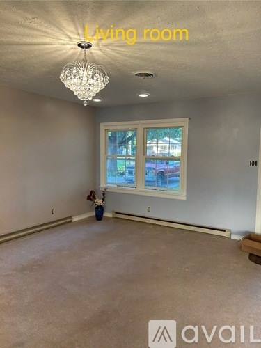 A living room with a chandelier and a window.