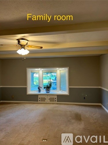 A family room with a window and a ceiling fan.