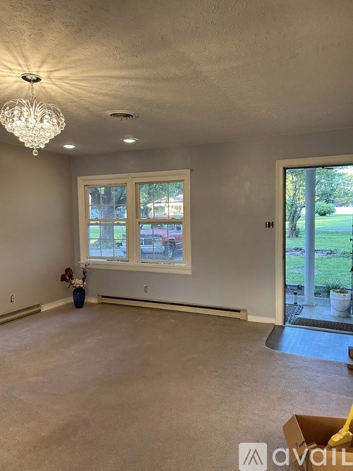 A room with a chandelier, a window, and a door leading outside.