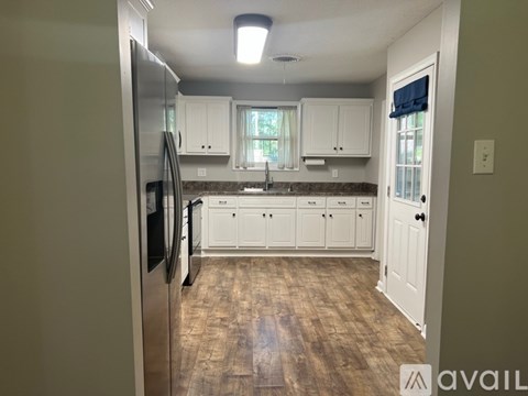 A kitchen with white cabinets and a stainless steel refrigerator.