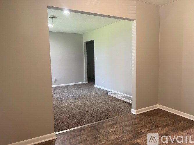 A room with a carpeted floor and a door on the right side.