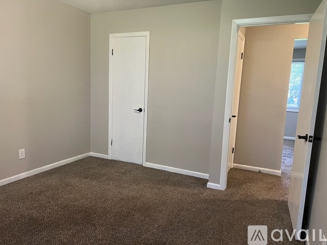 A room with a white door and carpeted floor.