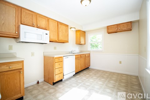 A kitchen with wooden cabinets and a white microwave.