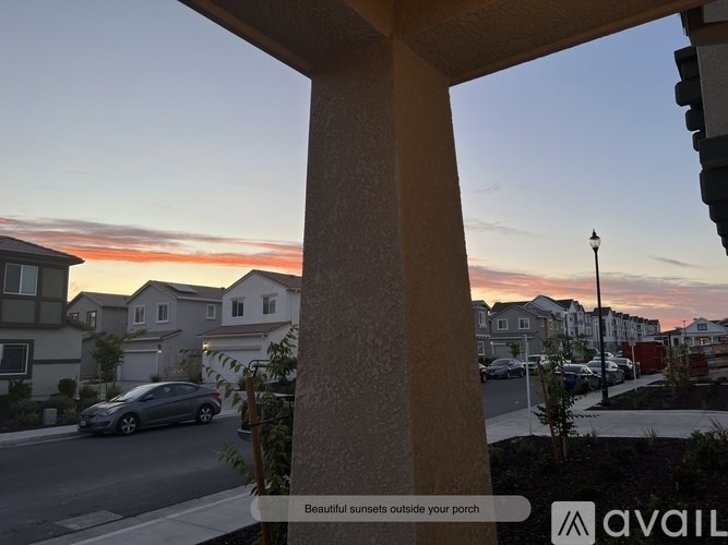 A view of a street from a porch with a car driving by.